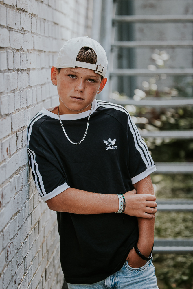 Tienershoot Dokkum. Portret van jongen met pet bij stalen trap door fotograaf Nickie Fotografie uit Friesland.