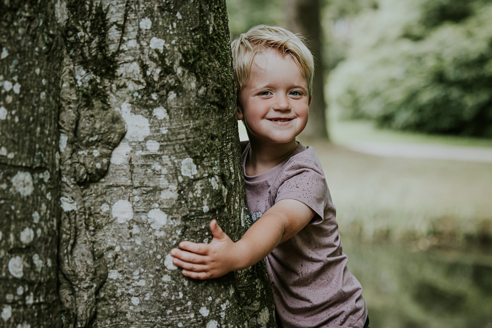 Kinderportret Friesland. Jongetje geeft de boom een knuffel. Portretfotografie door portretfotograaf Nickie Fotografie.