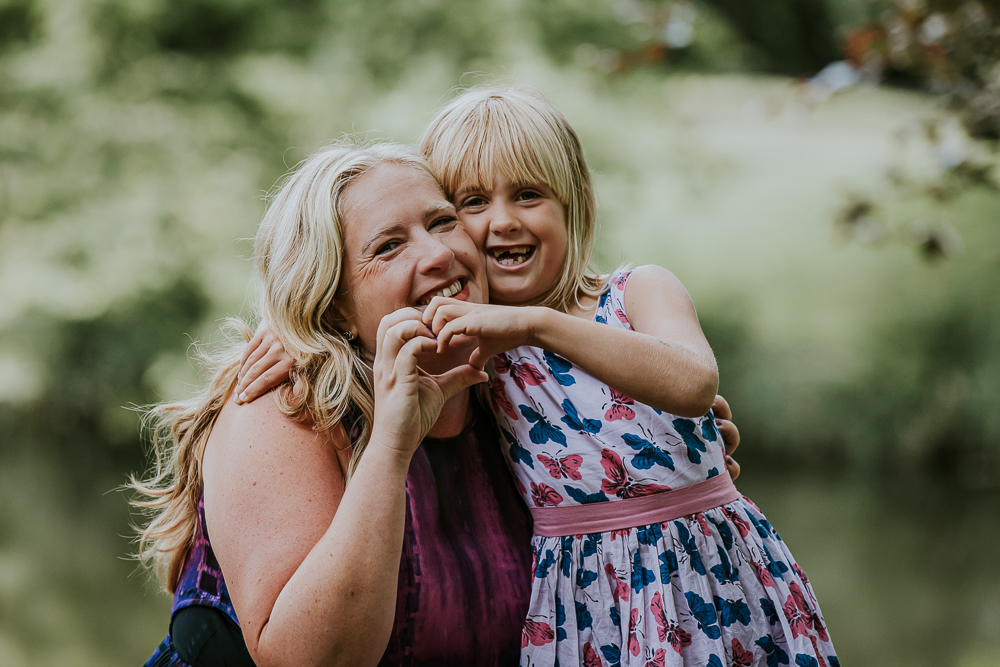 Portret van moeder en dochter. Ze maken samen een hartje met de handen. Fotoshoot door fotograaf NIckie Fotogafie uit Dokkum, Friesland.