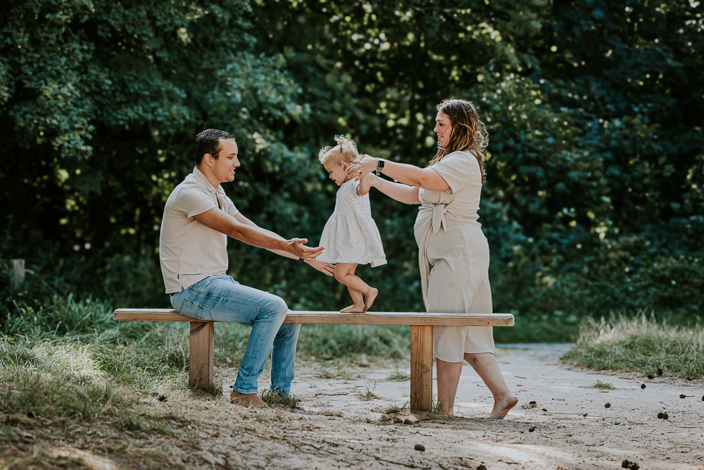 Gezinsshoot Friesland. De dreumes loopt over het houten bankje naar papa. Fotoreportage door gezinsfotograaf Nickie Fotografie uit Friesland.