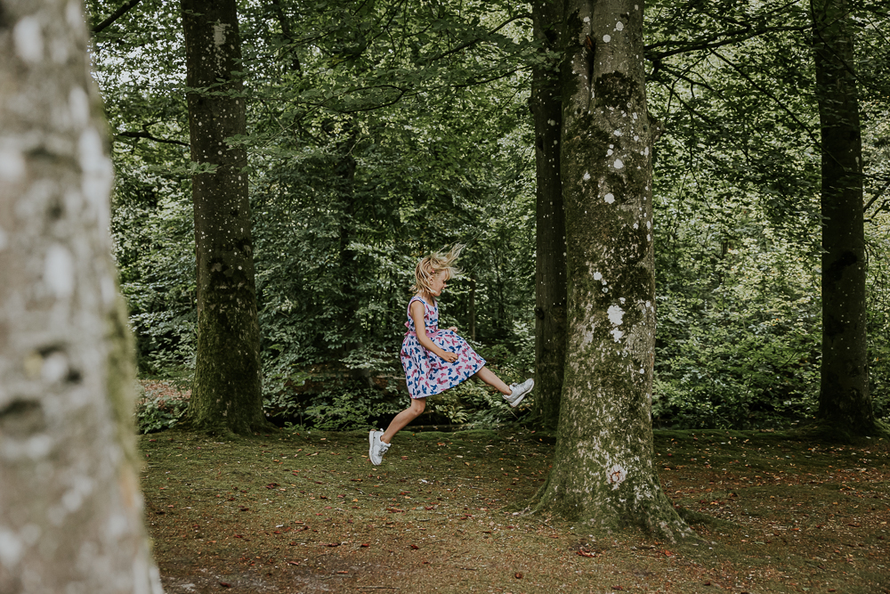 Gezinsshoot door fotograaf Nickie Fotografie. Meisje springt tegen de boom aan. 