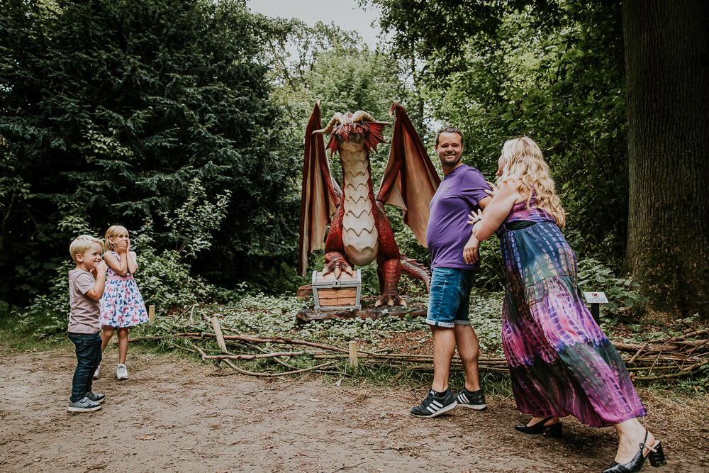 Mama laat papa schrikken bij de draak in het park der fabelen. Fotoshoot door fotograaf Nickie Fotogafie uit Friesland.