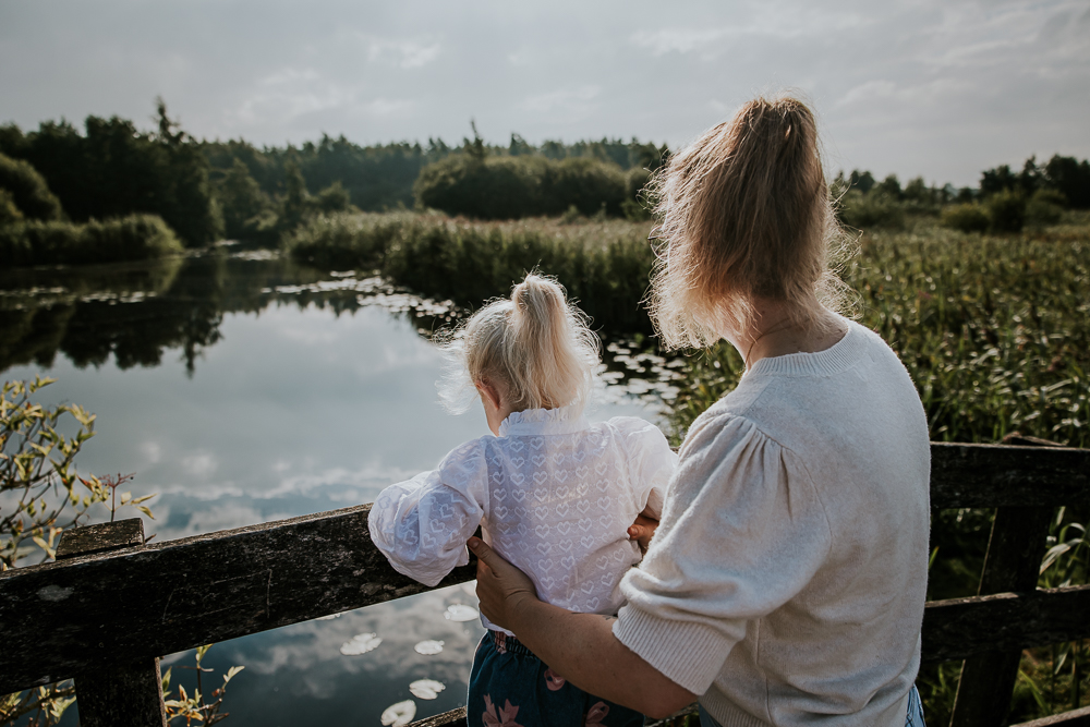 Gezinsfotografie Earnewâld door fotograaf Nickie Fotografie uit Friesland. Moeder en dochter kijken of er vissen zwemmen in de ven.