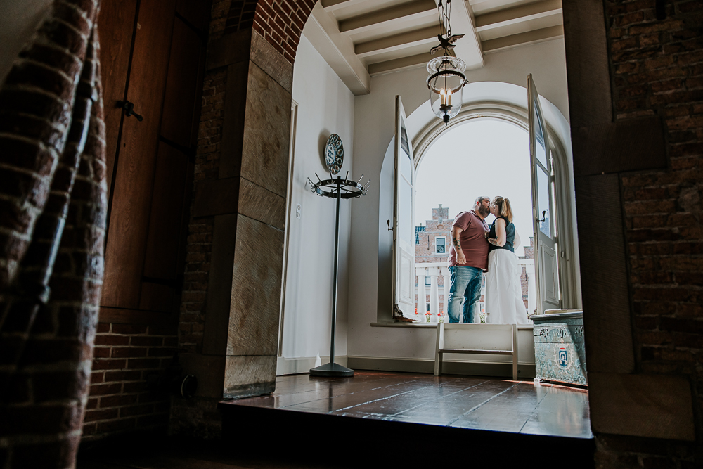 Balkonscene in het oude stadhuis van Dokkum. Het bruidspaar geeft elkaar een kus. Trouwreportage door huwelijksfotograaf Nickie Fotografie uit Friesland.