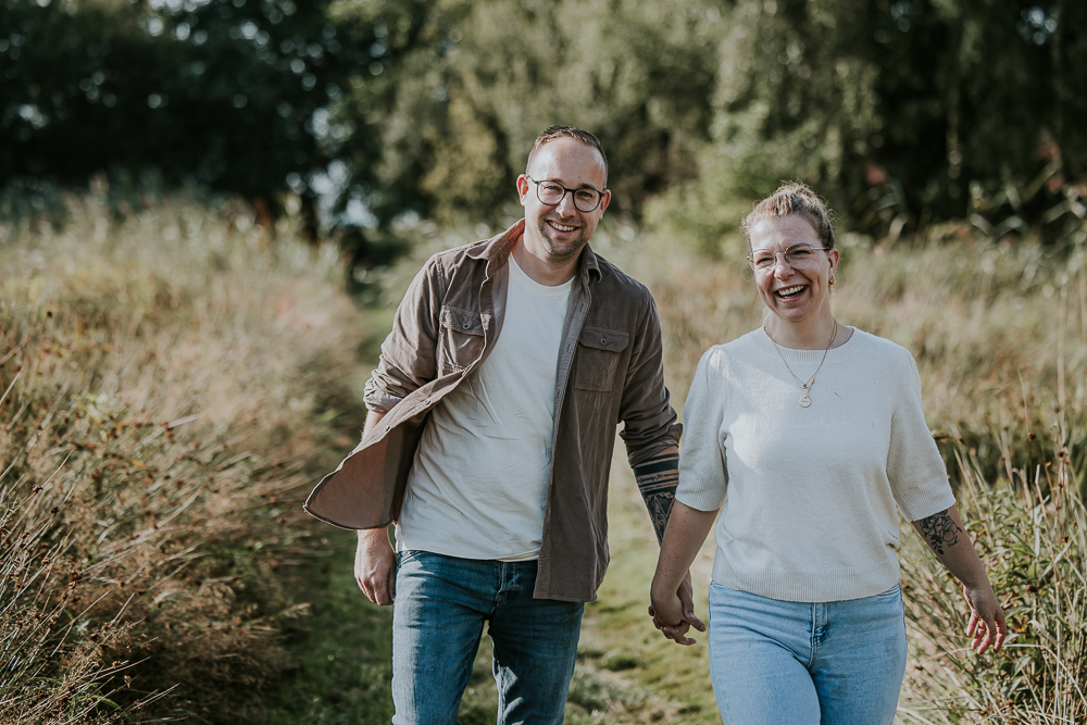 Fotoshoot Friesland. Portret van de ouders, hand in hand wandelend door de natuur door fotograaf Nickie Fotografie.
