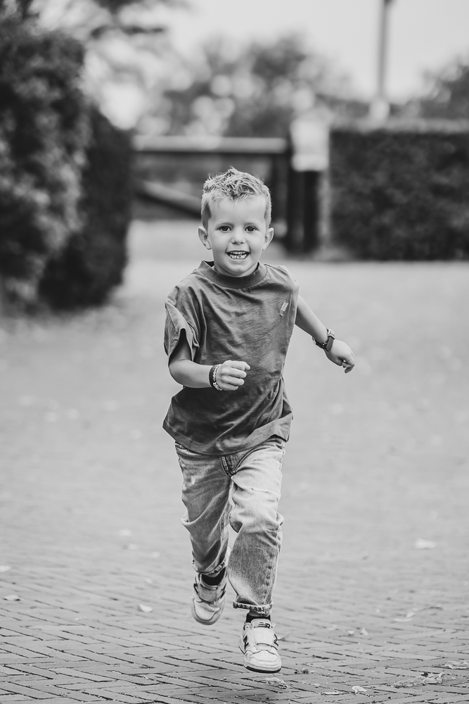 Zwart-wit portret van rennend jongetje door fotograaf Nickie Fotografie uit Dokkum, Friesland.