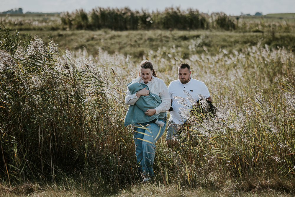 Fotoshoot Friesland. De ouders lopen door een mooi verlichte rietveld nabij Lauwersoog. Fotoreportage door fotograaf NIckie Fotografie.