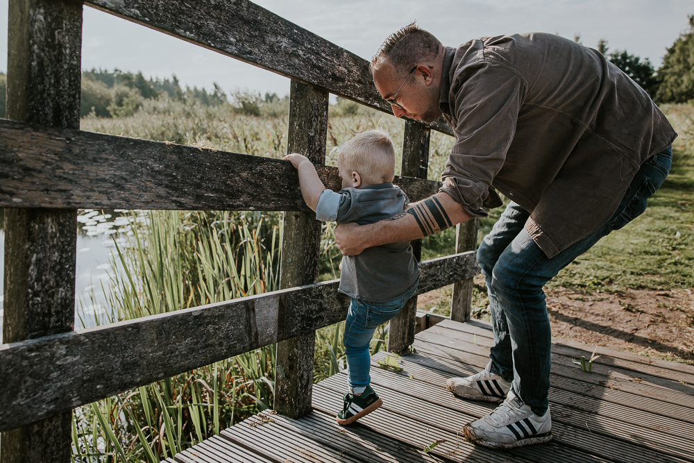 Fotoreportage Friesland. Vader helpt kleine zoon klimmen op de hek van de brug.