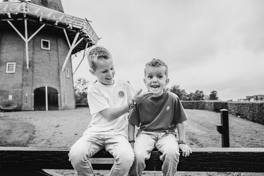 Familie fotografie Dokkum. De twee broertjes zitten op het hek bij de molen. Fotoshoot door fotograaf Nickie Fotografie uit Friesland.