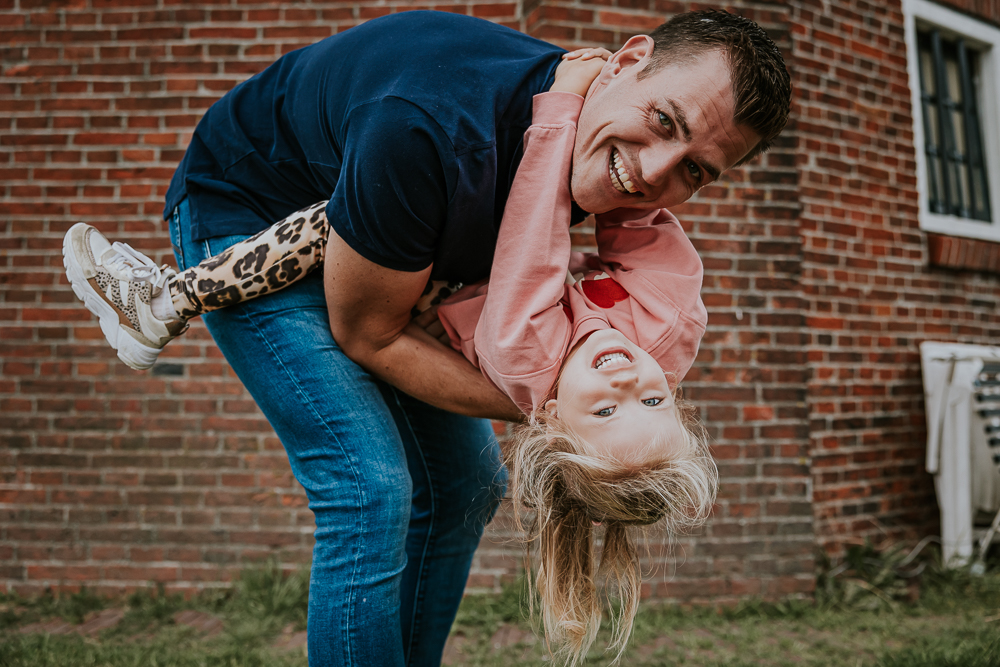 Fotoshoot Friesland. Vader is aan het stoeien met zijn dochter. Lifestyle fotografie door fotograaf Nickie Fotografie.