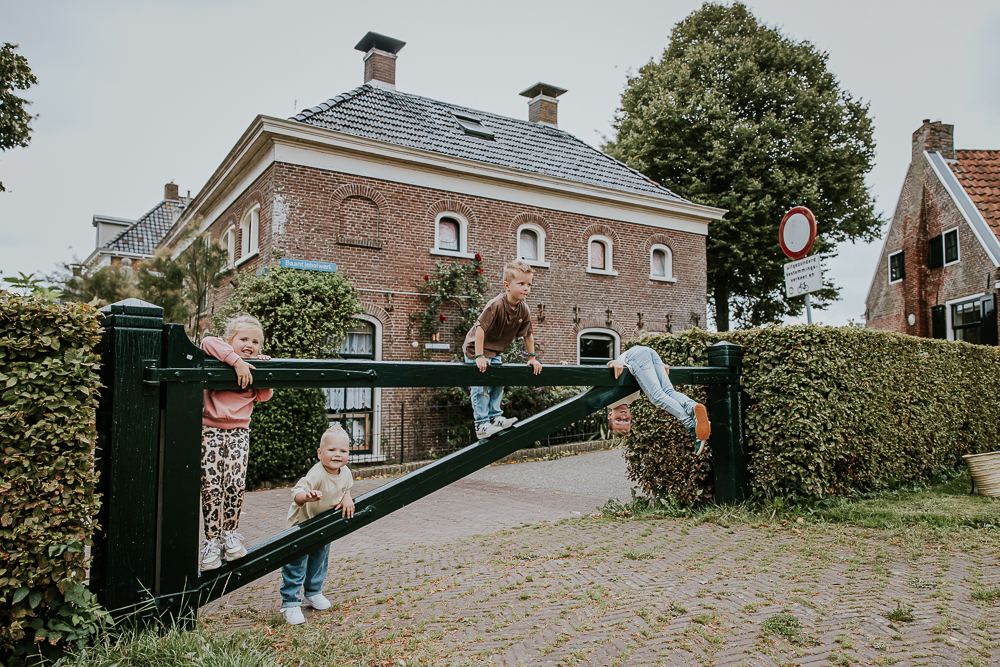 Fotoshoot Dokkum. Alle kinderen spelen bij het houten hek bij de molen. Fotoshoot door fotograaf Nickie Fotografie uit Friesland.