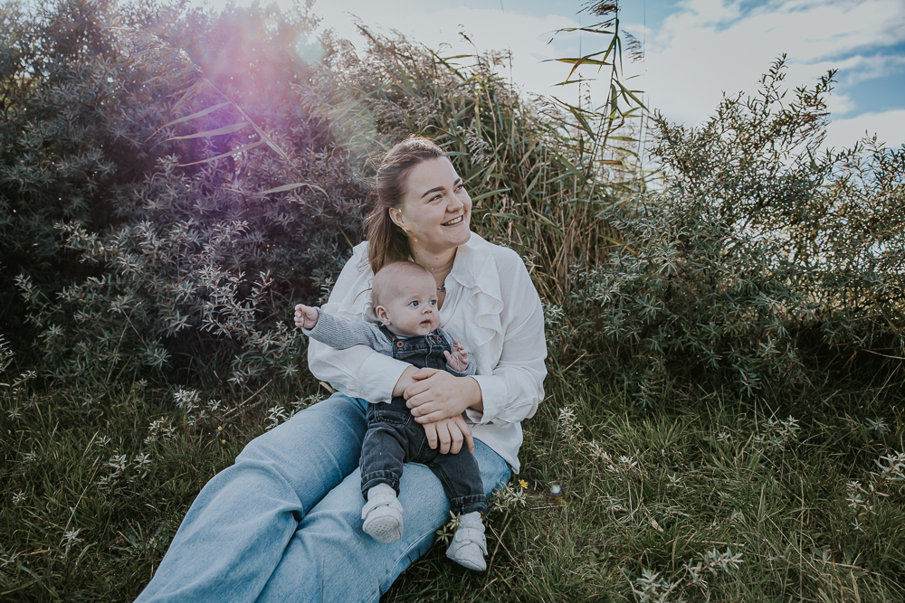 Fotoshoot Friesland. Portret van moeder met haar baby zoontje voor het riet in het nationaalpark Lauwersmeer door fotograaf Nickie Fotografie.