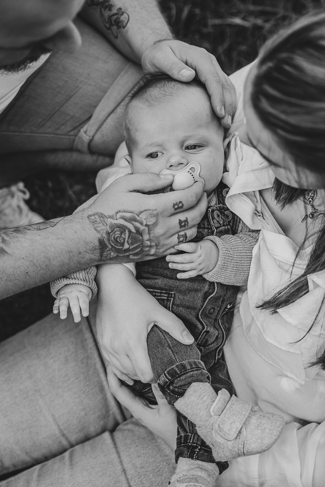 Babyfotografie Friesland. De baby ligt heerlijk in de armen van mama met een speen in de mond. Babyshoot door fotograaf Nickie Fotografie uit Dokkum, Friesland.