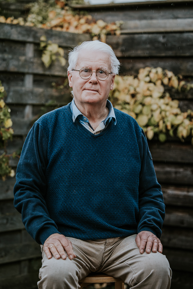 Senioren portret Dokkum. Man zittend op kruk voor de schutting door fotograaf Nickie Fotografie uit Friesland.