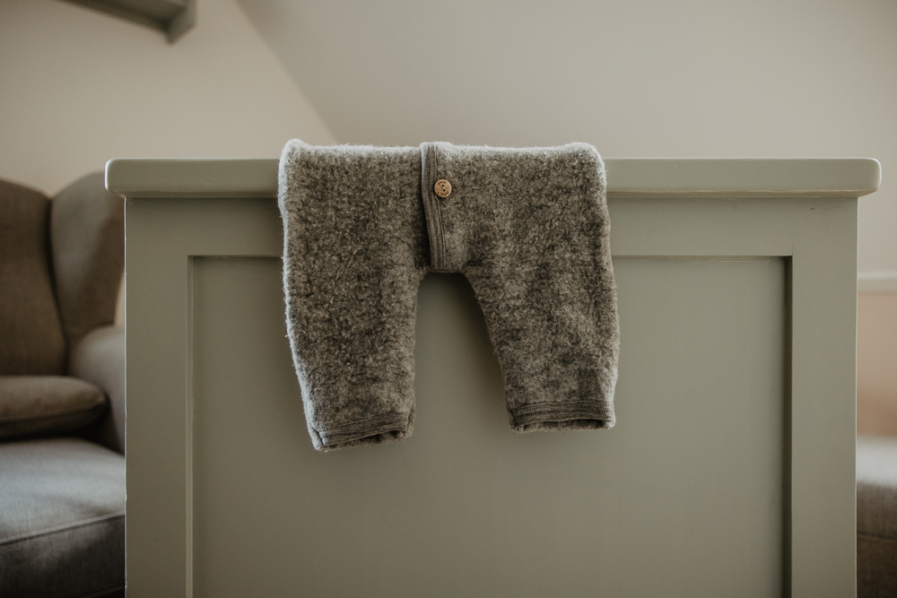 Fotograaf Friesland. Newbornshoot Tjalleberd. Foto van grijs babypakje op het rand van de ledikant.