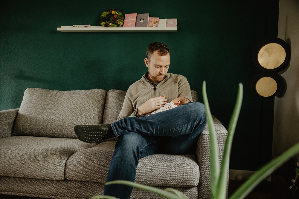 Newbornshoot Tjalleberd door fotograaf Nickie Fotografie uit Friesland. Papa zit met zijn kleintje op de bank.