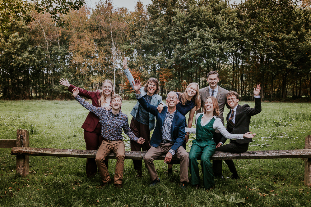 Vrolijke gezinsportret zittend op houten hek door fotograaf Nickie Fotografie uit Friesland.