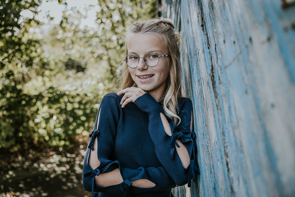 Fotograaf Friesland. Portret van tienermeisje leunend tegen oude blauwe houten schuurdeur door Nickie Fotografie uit Dokkum.