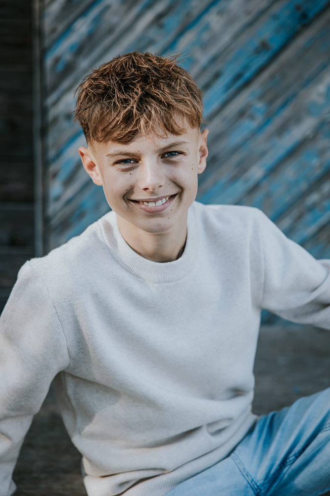 Portret van puber bij oude houten muur met diagonale blauwe planken. Fotoshoot Friesland door fotograaf Nickie Fotografie uit Dokkum.