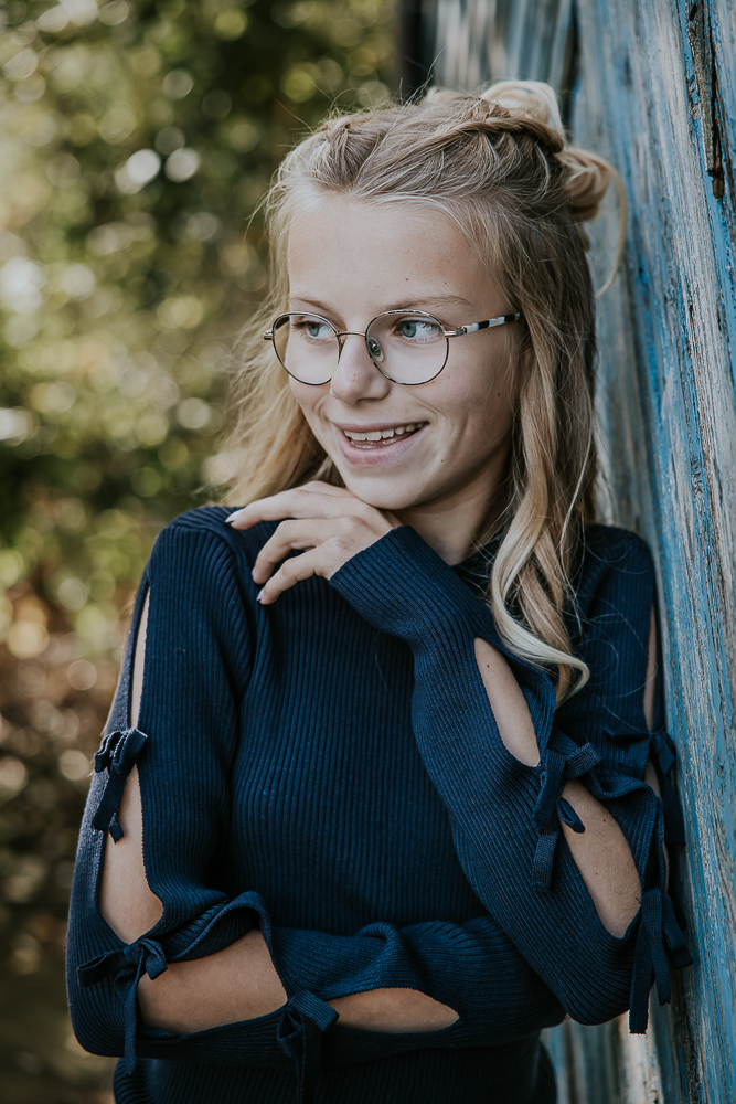 Fotograaf Friesland. Portret van tienermeisje leunend tegen oude blauwe houten schuurdeur door Nickie Fotografie uit Dokkum.