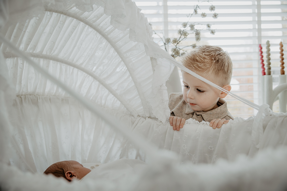 Fotograaf Dokkum. Grote broer kijkt naar zijn baby broertje in de wieg. Lifestyle fotografie door Nickie Fotografie uit Friesland.