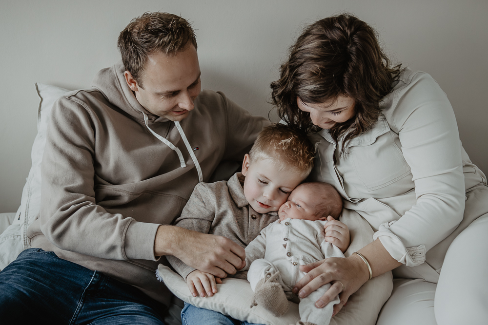 Gezinsshoot Friesland. Gezinsportret waarbij de grote broer zijn babybroertje liefdevol een knuffel geeft. Fotoreportage door fotograaf Nickie Fotografie.