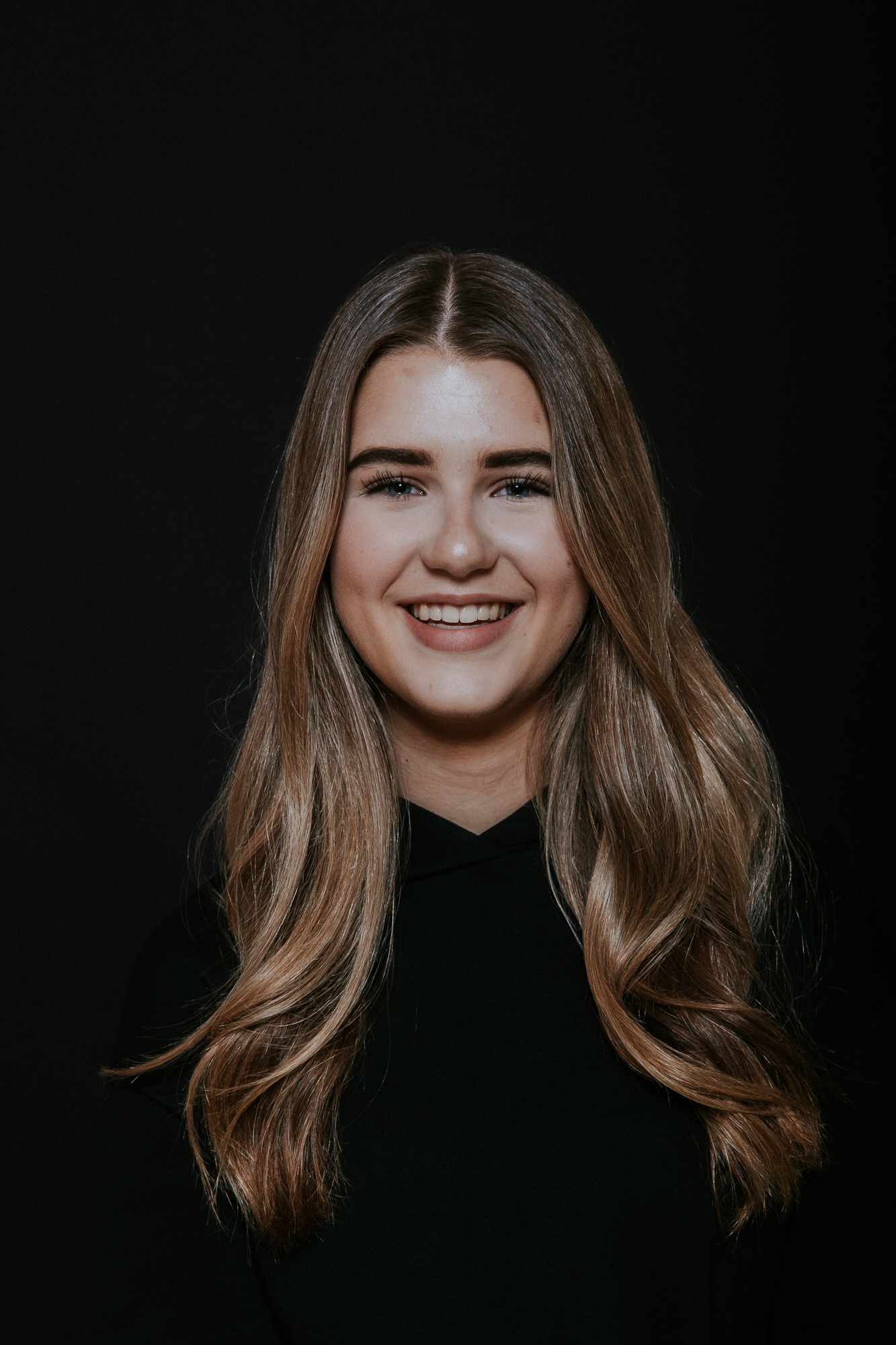 Gezellig zwart-wit portret van broer en zus in zwarte kleding in de studio met zwarte achtergrond door fotograaf Nickie Fotografie uit Dokkum, Friesland.