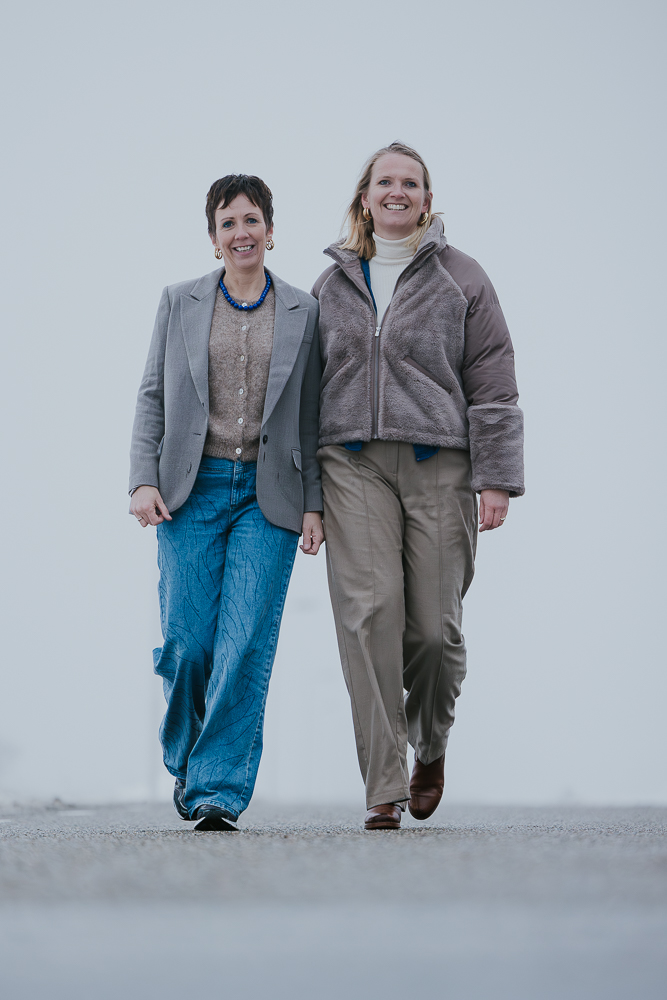 Vriendinnenshoot Friesland door fotograaf Nickie Fotografie. De vriendinnen lopen op de weg in de dichte mist.