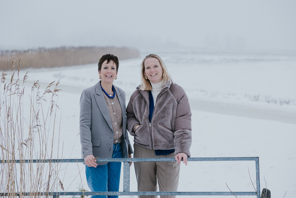 Fotoshoot Friesland. Portret in de sneeuw van vriendinnen bij het hek van een weiland. Fotoreportage door fotograaf Nickie Fotografie uit Dokkum.