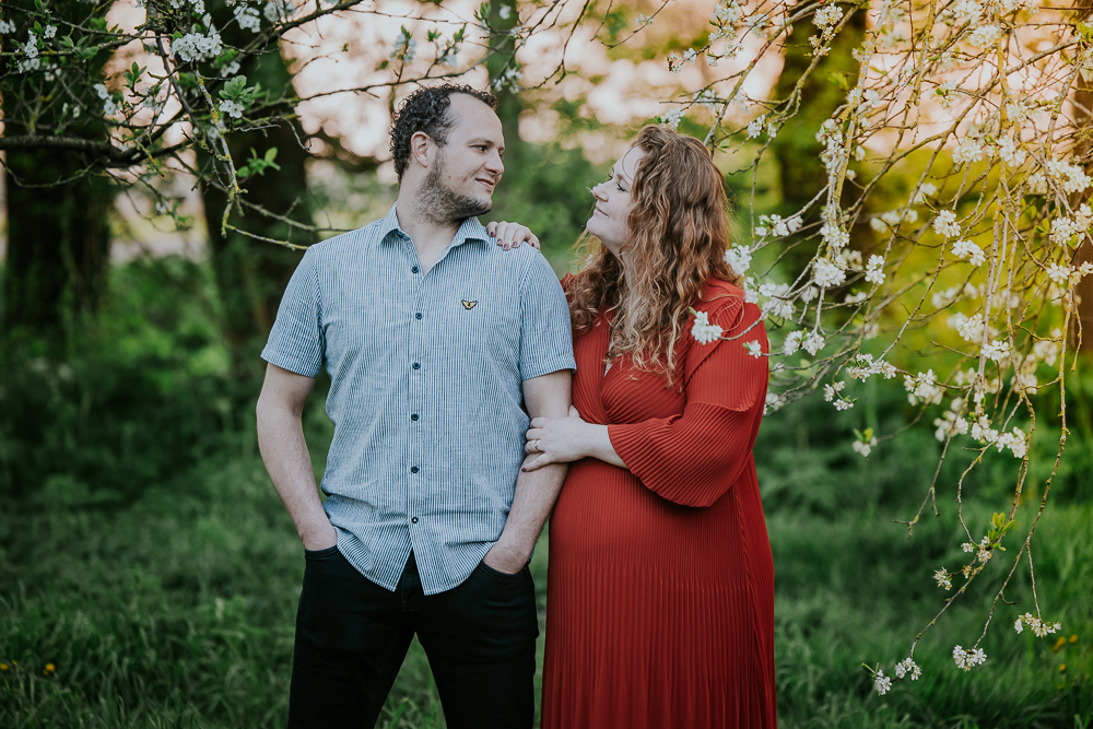 Fotograaf Friesland. Zwangerschapsshoot met partner tussen de bloeinde fruitbomen door Nickie Fotografie.