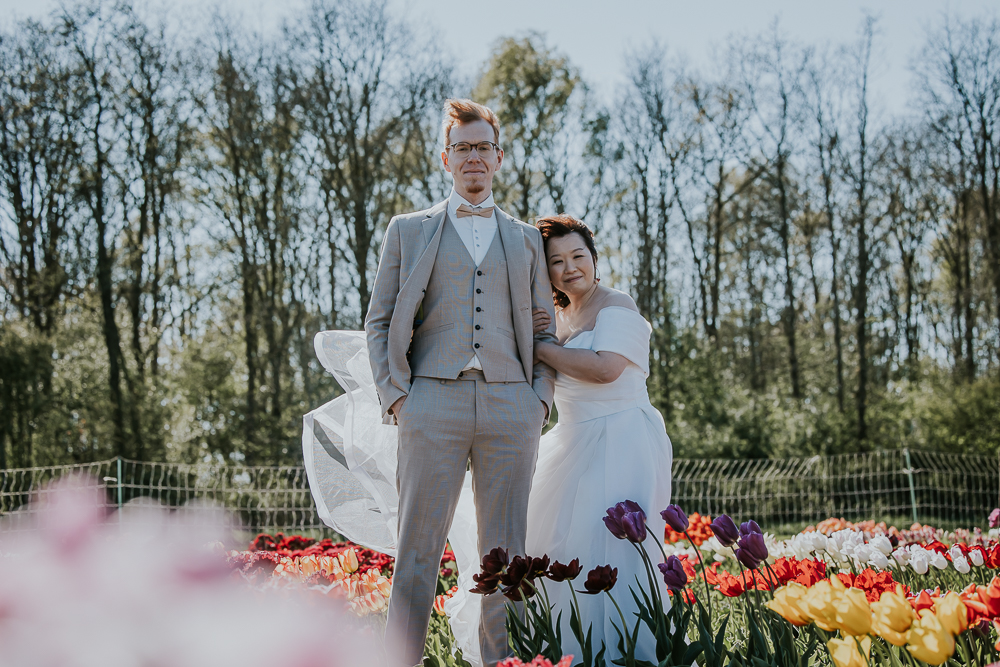 Fotograaf Friesland. Portret van bruidspaar in gekleurde tulpenveld door Nickie Fotografie.