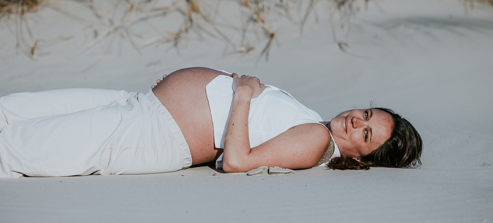 Zwangerschapsshoot Schiermonnikoog, liggend op het strand. Bolle buik reportage door fotograaf Nickie Fotografie uit Friesland.
