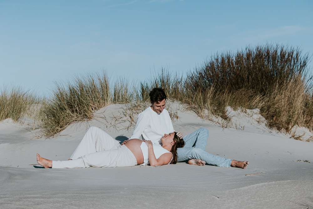 Zwangerschapsreportage op het strand, Lekker liggend en zittend op het zand. Fotoshoot door fotograaf Nickie Fotografie uit Friesland.