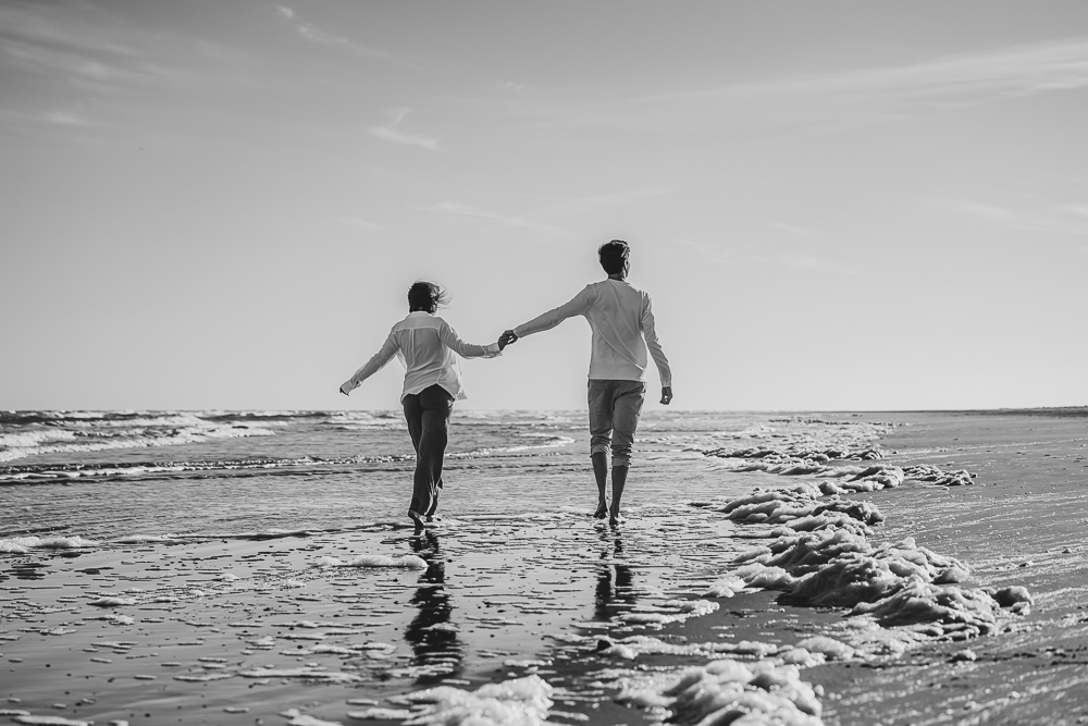 Fotoshoot op het strand door fotograaf Nickie Fotografie uit Friesland. Hand in hand lopend door de branding.