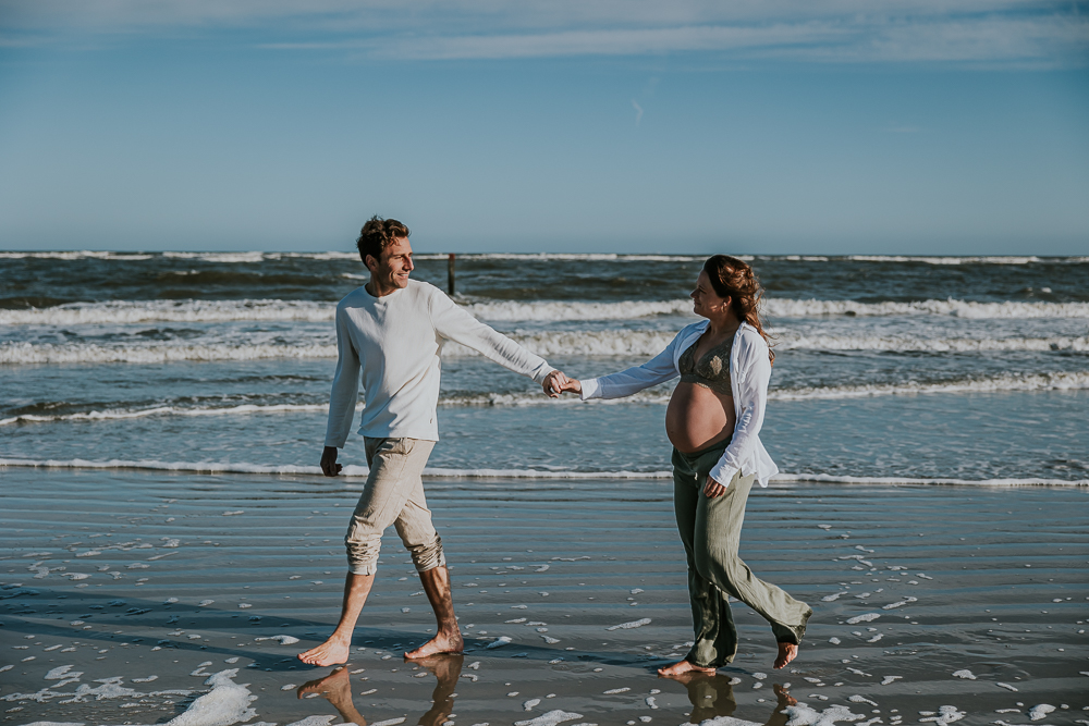 Zwangerschapsshoot Schiermonnikoog door fotograaf Nickie Fotografie uit Friesland. Samen wandelend op blote voeten door de branding.