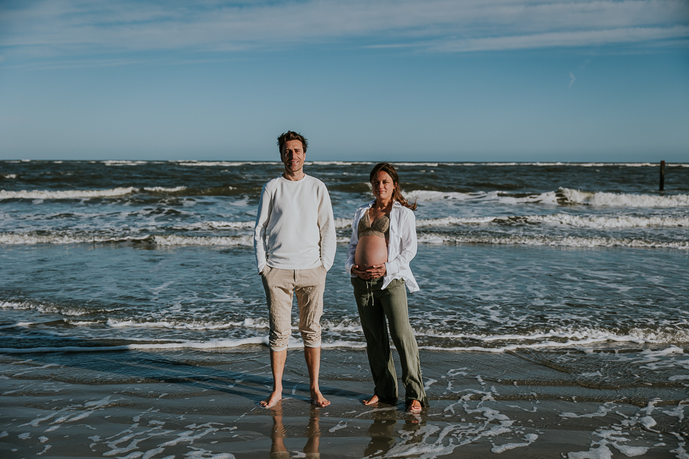 Fotoshoot Schiermonnikoog. Bolle buik reportage met partner door fotograaf Nickie Foografie. Met de blote voeten in het water.