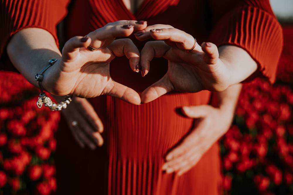 Zwangerschapsreportage Friesland. De aanstaande moeder vormt een hartje met haar handen voor haar bolle buik. Fotoshoot door fotograaf Nickie Fotografie uit Dokkum.