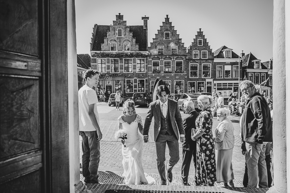 Fotograaf Dokkum. Het bruidspaar gaat de oude Stadhuis binnen met op de achtergrond de mooie trapgevels op de Zijl. Trouwreportage door Nickie Fotografie.