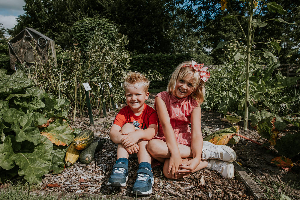 Kinderportret van zus en broer in de moestuin bij de courgettes door fotograaf Nickie Fotografie.