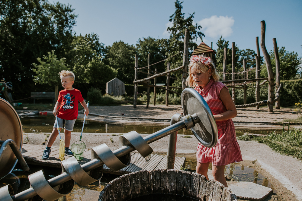 fotograaf Friesland. Gezinsshoot in de speeltuin van De Kruidhof in Buitenpost. De kinderen zijn bij de waterpompen aan het spelen. Fotoshoot door Nickie Fotografie.