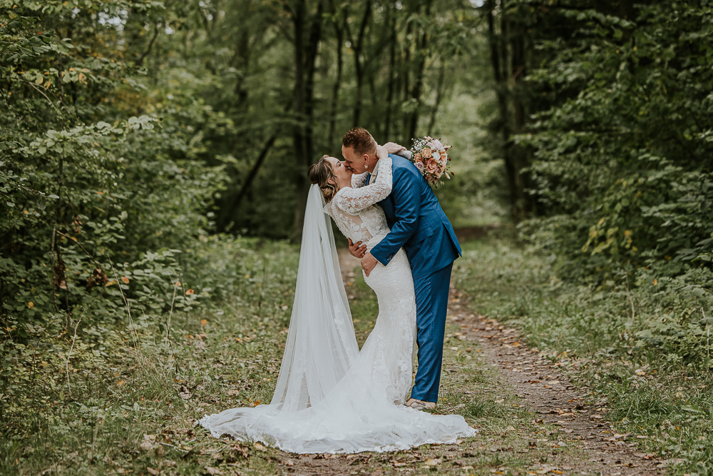 Een liefdevolle kus tijdens de bruidsshoot in het bos.