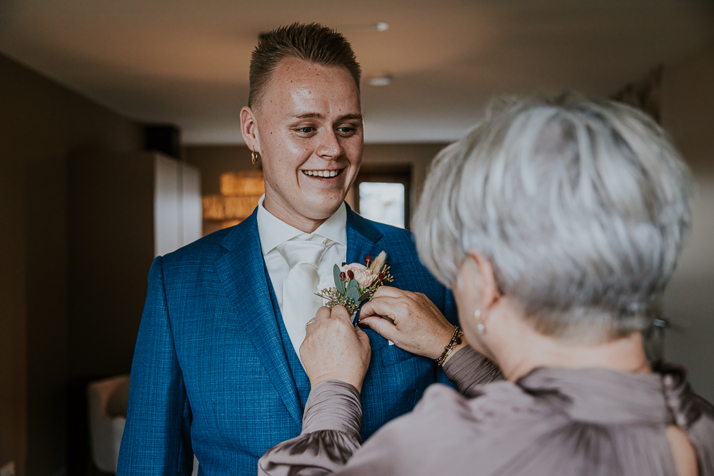 Moeder helpt de bruidegom met de corsage.