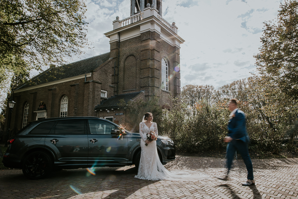 Bruidegom loopt langs zijn bruid voor de auto.