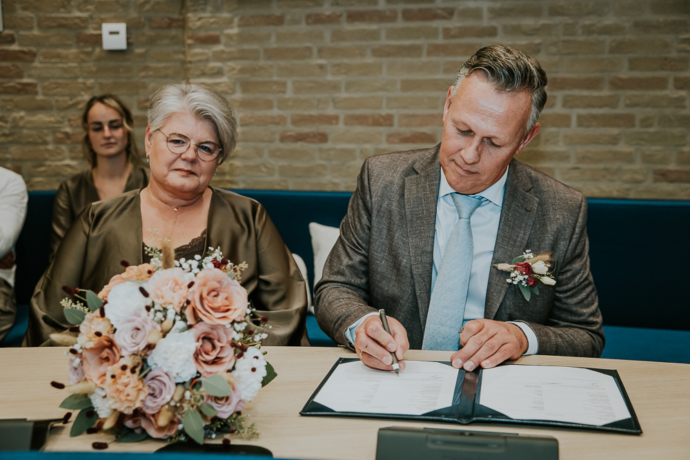 De getuige ondertekent de huwelijksakte.